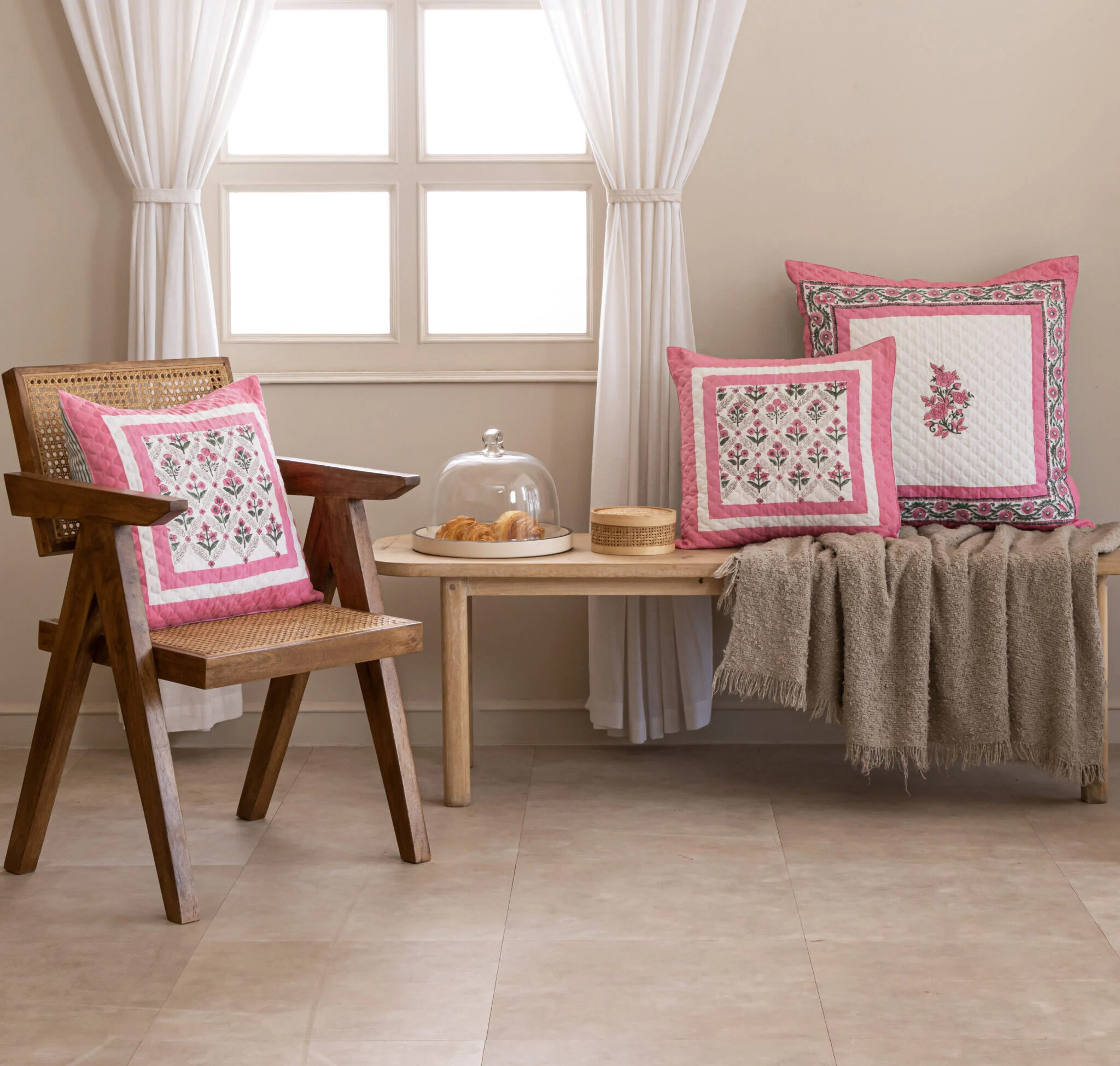 Pink bordered hand block printed cushion covers on a cane chair and bench