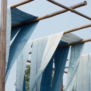 Hand block printed fabric drying in the sun on bamboo poles