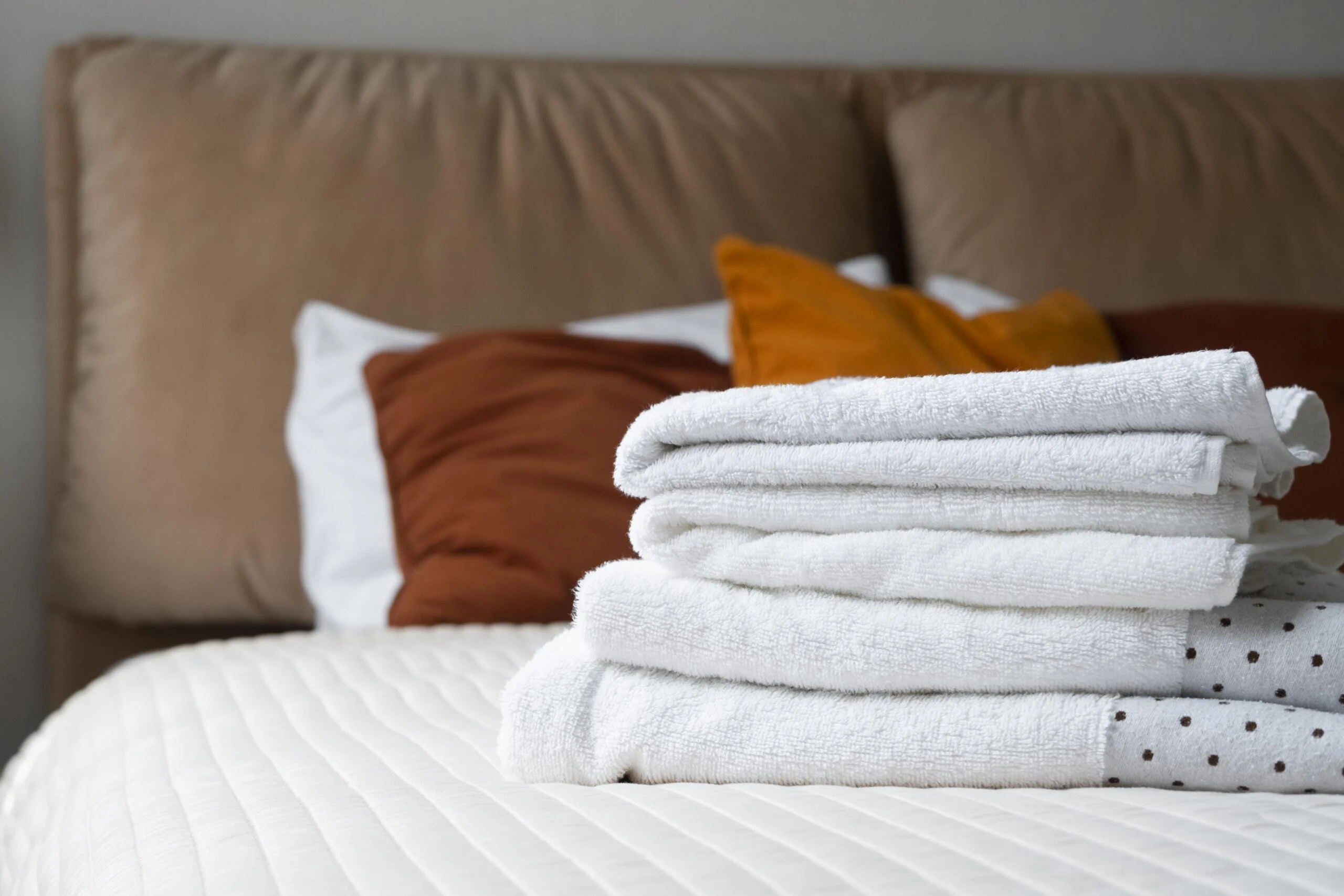 Folded white linens on a made bed