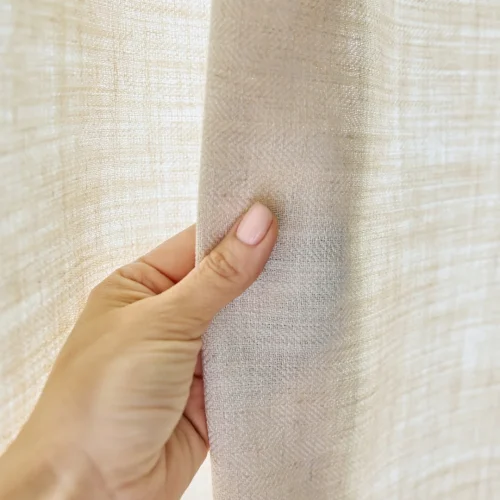 Hand holding natural linen fabric showing its weave